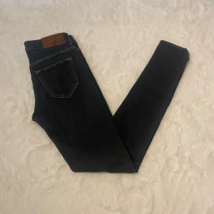 Mörkblå jeans från Tiger of Sweden 30/32 - Snygga mörkblå jeans från Tiger of Sweden med klassisk femficksdesign och kontrasterande gula sömmar. Modellen heter Slight och byxorna är tillverkade i Italien. Perfekta för dig som gillar stilrena och tidlösa jeans.