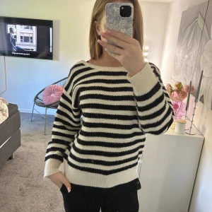 Randig stickad tröja med rosett i ryggen - Säljer en svartvit stickad tröja med breda ränder och snygg rosettdetalj i ryggen. Tröjan har lång ärm, öppen rygg och är lite loose i passformen. Perfekt för dig som gillar en chill men ändå unik look.