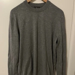 Grå slim fit tröja från H&M - Säljer en stilren grå långärmad tröja från H&M i slim fit-modell. Tröjan har rund halsringning och är tillverkad i ett mjukt material som passar perfekt till lager-på-lager. Enkel och clean look som funkar till det mesta.