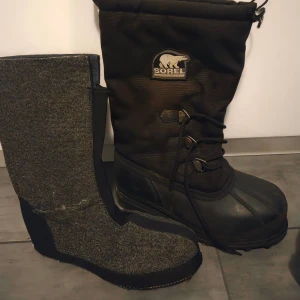 Sorel Glacier vinterstövlar herr 45 - Säljer ett par svarta Sorel Glacier vinterstövlar i storlek 45. Stövlarna har grov sula för bra grepp, snörning framtill och varm innersko i filtmaterial. Perfekta för kalla vinterdagar och snö. Yttermaterial i syntet och gummi, innerfoder av polyester och återvunnen polyester.