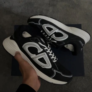 b30 Svart vita sneakers med vita detaljer - Säljer ett par svart vita  b30 sneakers med vita och silvriga detaljer. Skorna har en chunky vit sula och meshpartier för extra andningsförmåga. Klassisk snörning och modern design som sticker ut.