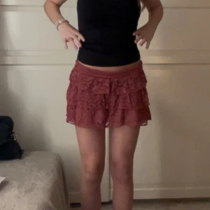 Volangkjol i spets från stradivarius  - Supersöt röd kjol från stradivarius med flera lager volanger och spetsdetaljer. Kjolen har små shorts under och har aldrig använts utöver dessa bilder💗