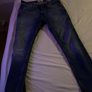 Blå Replay jeans  - Snygga blå jeans från Replay med klassisk femficksdesign och raka ben. Jeansen har subtila slitningar och kontrastsömmar på bakfickorna. Perfekt passform och stilren look som funkar till det mesta. Mjukt och slitstarkt jeanstyg.