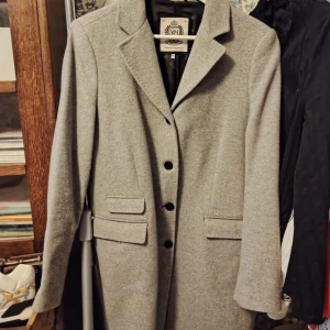 NEWHOUSE Grå Vinterkappa i Ull [stl 42]  - Snygg grå kappa från Newhouse(5500kr i butik) i klassisk rak modell med krage och tre knappar framtill. Knappt använd. Nyskick. Kappan har två fickor med lock och är helfodrad. Perfekt för dig som gillar stilrena och tidlösa plagg.