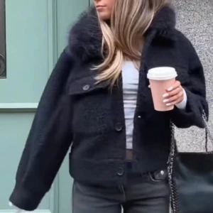 Mörkblå kappa  - Snygg svart teddyjacka med stor fluffig krage och knappar framtill. ärmar. Perfekt för dig som vill ha en trendig och mysig look i höst och vinter. Storlek 170 passar xs/s