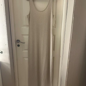 Beige ribbad maxiklänning från Pieces - Säljer en beige ribbad maxiklänning från Pieces i storlek M. Klänningen är ärmlös med rundad halsringning och har en snygg, figurnära passform. Perfekt för dig som gillar en enkel men trendig look. Materialet är mjukt och stretchigt för extra komfort.