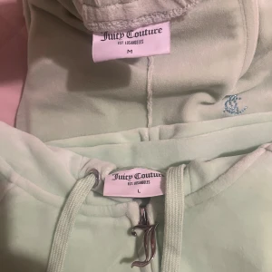 Mintgrön Juicy Couture hoodie med strass - Superfin mintgrön hoodie från Juicy Couture i mjuk velour med blå strassdetaljer och broderad JC-logga. Hoodien har huva, snörning och en stor Juicy-text i blå strass på ryggen. Perfekt för dig som vill ha en ikonisk och trendig look.