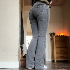 Grå bootcut jeans från Perfect Jeans - Säljer ett par grå jeans från Perfect Jeans i storlek 32. Modellen har låg midja och bootcut-ben, vilket ger en snygg siluett. Jeansen är i stretchigt denim och har klassiska fickor både fram och bak. Perfekta för dig som gillar en avslappnad men trendig look.