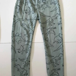 Mjukisbyxor strl 122/128 dinosaurier - Lite slitage på knäna men inga hål  Noppor finns Resåren i midjan är lite vriden men funkar ändå  Liten dov fläck baktill   Byxor Mjukis  Dino