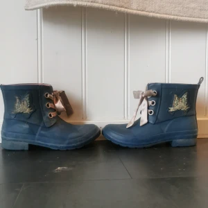 Blå Odd Molly boots med satinband - Snygga blå boots från Odd Molly med rund tå och platt sula. Dekorerade med ett fjärilsmärke på sidan och satinband som snörning, samt en liten metallbricka med texten 'myself unltd'. Perfekta för dig som vill ha något unikt och coolt i garderoben.