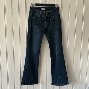 Blå bootcut jeans från Madlady - Snygga blå jeans från Madlady med bootcut passform. Jeansen har två stora framfickor, dubbla knappar i midjan och bakfickor med lock och knapp. Klassisk denim med kontrastsömmar och lätt tvättad look. Jätte fint skick 