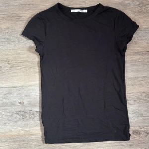 Svart basic t-shirt från Lager 157 - En svart, enkel t-shirt från 157 med rund halsringning och korta ärmar. Modellen är klassisk och passar perfekt till jeans eller shorts. Tillverkad i mjuk bomull för en skön känsla hela dagen.