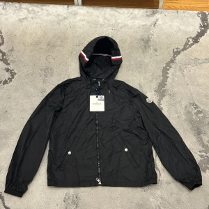 Svart vindjacka från Moncler med huva - Svart Moncler Grimpeurs Windbreaker i storlek M med NFC kommer även med alla tags. Helt ny, Skriv ifall ni vill ha flera bilder eller är intresserade 