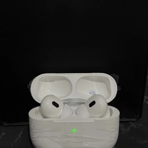 AirPods Pro med iPhone sladd - Apple AirPods Pro trådlösa hörlurar med laddningsetui. Produkten ser ut att vara i nyskick med skyddsplast kvar på etuiet. Levereras med laddningskabel. Perfekt för brusreducering och hög ljudkvalitet.