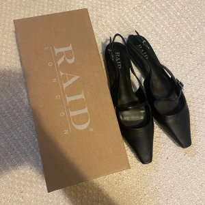 Spetsiga, platta slingbacks från Raid - Svarta slingbacks från Raid i syntetiskt läder. Justerbart spänna fram och bak. Aldrig använda. Storlek 39