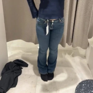 Blå bootcut jeans med hög midja - Säljer ett par blå jeans med bootcut-modell och hög midja. Jeansen har klassisk femficksdesign, dragkedja och knapp framtill. Materialet är jeans med lätt stretch och snygg tvättad look. Perfekta för dig som gillar en tidlös och trendig stil.