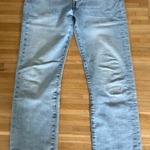 Levi's 501 ljusblå jeans W30 L30 - Ljusblå Levi's 501 jeans med klassisk rak passform och femficksdesign. Jeansen har en snygg tvättad look och är tillverkade i slitstarkt bomullsjeans. Liten lagning på ena benet!