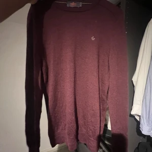 Vinröd merinoullströja från Morris - Säljer en vinröd stickad tröja från Morris i 100% merinoull. Tröjan har rund halsringning, lång ärm och en liten broderad logga på bröstet. Perfekt för dig som gillar klassisk och stilren look.