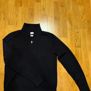 Mörkblå merinotröja These Glory Days - Mörkblå långärmad tröja från These Glory Days i mjuk och lyxig merinoull. Tröjan har en hög krage med half zip-dragkedja framtill och en clean, stilren look. Perfekt för dig som gillar minimalistisk stil och vill ha något som känns extra skönt mot huden. Modellen är 173cm lång och väger cirka 70kg.