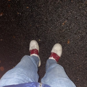 Valentino Garavani Open sneakers vit/röd - Säljer ett par Valentino Garavani Open sneakers i vitt skinn med bred röd läderdetalj över vristen. Klassisk rund tå, platt sula och diskreta nitar på sidan. Snygg och stilren design som sticker ut med den röda detaljen.