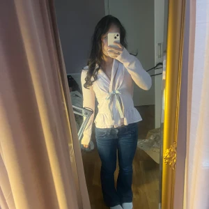 Rosa odd Molly kofta💕 - Supersöt ljusrosa kofta från Odd Molly med diskret mönster, volangkant nertill och grått knytband i midjan. Långärmad och mjuk i bomullsmix, perfekt för vår och höst. Broderad logga och nummer på ryggen ger extra detalj🥰😚