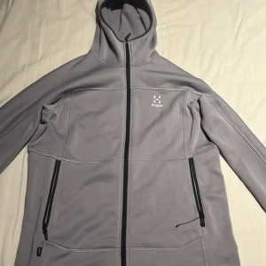 Grå fleecehoodie från Haglöfs dam M - Tja! Säljer en grå hoodie från Haglöfs i fleece, dammodell i storlek M. Tröjan har hel dragkedja, två sidofickor med dragkedja och en skön huva. Perfekt för kyliga dagar! 