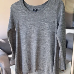 Grå stickad tröja  - Enkel och stilren grå stickad tröja från H&M i storlek XS. Tröjan har rund halsringning, långa ärmar och ribbade muddar vid ärmslut och nederkant. Perfekt för lager-på-lager och chill vardagsstil.