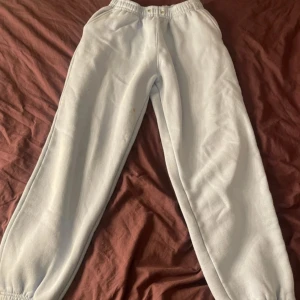 Ljus blåa mjukisbyxor med strassdetalj - Ljusblåa mjukisbyxor med resår i midjan och vid benslut. På baksidan finns texten 'NASTY' i glittriga strasstenar som verkligen poppar. Byxorna är i mjukt bomullsmaterial och har en loose passform, perfekta för chill dagar. Lite foundation fläckar men går bort med medel.