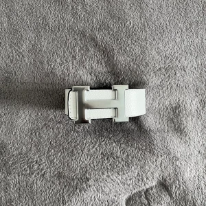 Hermés Bälte  - Snyggt vändbart bälte i vitt och svart skinn med ett stort H-format spänne i silverfärgad metall. Bältet har stilren design och är perfekt för att lyfta vilken outfit som helst. Bredden är klassisk och materialet känns lyxigt och hållbart.