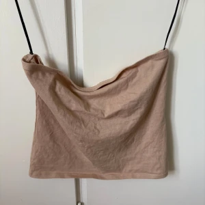 Beige tubtopp från Divided H&M - Säljer en enkel och stilren beige tubtopp från Divided H&M. Toppen är ärmlös och har en rak, croppad passform med mjukt bomullsmaterial. Perfekt att matcha med jeans eller kjol för en chill look.