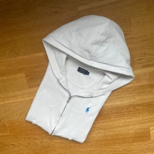 Polo Ralph Lauren but zip up hoodie Äkta  - Polo Ralph Lauren Vit Zip-Up Huvtröja  🧢 Storlek: Unisex Small 📏 Mått: 	•	Midja: 43 cm × 2 	•	Längd: 54 cm 	•	Axel till axel: 38 cm 	•	Ärmlängd: 57 cm  🧼 Skick: Utmärkt skick – inga defekter  Denna huvtröja har dragkedja framtill och är tillverkad i en mjuk bomullsblandning. Den är mångsidig och passar perfekt för vardagligt bruk.  ✅ Äkthet garanterad 📩 Öppen för bud – skicka gärna ett meddelande vid frågor. 🚚 Frakt: Skickas samma dag eller inom 24 timmar.  #PoloRalphLauren #Hoodie #VitHoodie #U