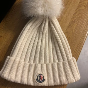 Moncler mössa - Så fin Moncler mössa med boll, har tyvärr blivit fläckar på insidan av smink men inget som syns när man har på sig den🤍