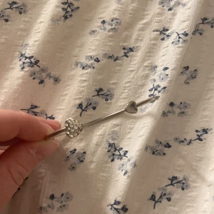 Silverfärgat armband med hjärtan - Snyggt armband i silverfärg med två hjärtformade detaljer, varav ett är dekorerat med glittrande stenar. Aldrig använt 🥰