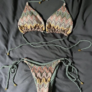 Missoni Mönstrad bikini med snörning XS - Snygg helt ny bikini i storlek XS med sicksack mönster i grönt, gult, rosa och rött. Toppen har trekantsform och knyts i nacken och ryggen med tvinnade snören med guldfärgade detaljer. Underdelen har knyt i sidorna. 