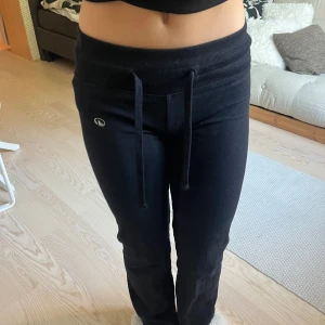 Svarta lågmidjade mjukisbyxor med snörning - Svarta mjukisbyxor från decathlon med låg midja och bred resår. Byxorna har snörning i midjan och en liten logga på ena benet. Sköna och stretchiga i bomullsmix, perfekta för chill eller träning. 😊