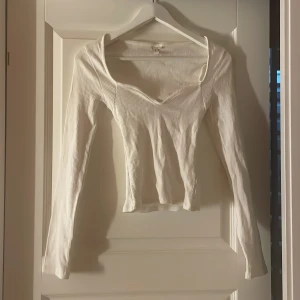 Vit ribbad långärmad topp - Säljer en vit ribbad topp med lång ärm och snygg v-ringad hals. 