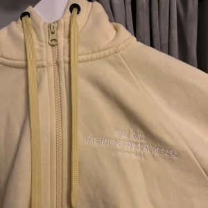Gul hoodie från Peak Performance XS - Ljusgul hoodie från Peak Performance med dragkedja, huva och snörning. Väldigt bra skick, dock en svart fläck på ärmen på sista bilden. Har inte provat att ta bort så kan vara möjligt om man vill fixa till den!💛