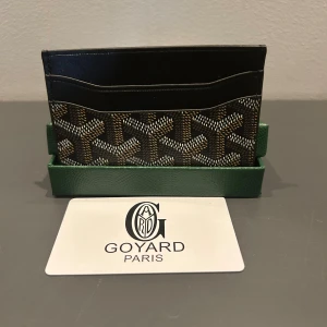  plånbok med ikoniskt mönster - Slimmad och lyxig plånbok fmed det klassiska handmålade mönstret i svart, brunt och vitt. Plånboken har flera fack för kort och sedlar, samt en insida i gul skinn. Perfekt för dig som vill ha något exklusivt och stilrent i fickan.