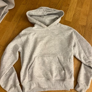 Ljusgrå hoodie med huva - En stilren ljusgrå hoodie med klassisk huva och magficka. Säljer då den inte kommer till användning 