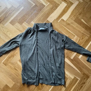 Grå kofta med dragkedja - Snygg olivgrön kofta från Selected Homme med dragkedja framtill och hög krage. Långärmad och tillverkad i mjukt material. Enkelt att matcha med Jeans