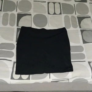 Svart tight kjol från Gina Tricot - Enkel och stilren svart kortkjol från Gina Tricot. Kjolen är tight och har en rak passform, perfekt att matcha med en crop top eller oversized tröja. Gjord i stretchigt material för en bekväm känsla. Storlek:L