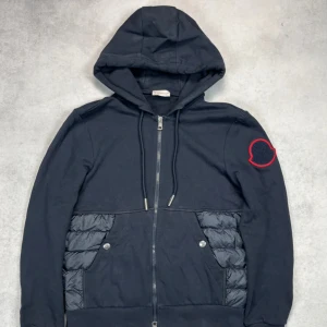 Moncler hooded cardigan jacket - – Condition: 8/10 - general wear  - Size: M  – Retail price: 10 000 + SEK  Please note that Moncler runs small, we recommend going up one size from your usual size.