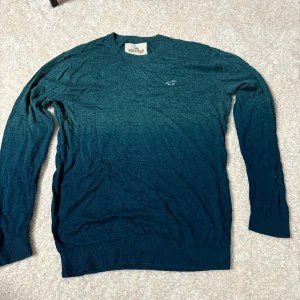 Blå stickad tröja från Hollister - Mysig stickad tröja från Hollister i en snygg blå nyans med diskret logga på bröstet. Tröjan har rund halsringning, lång ärm och ribbade muddar. Perfekt för lager-på-lager och chill dagar.