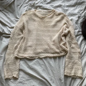 Beige stickad tröja - Superfin beige stickad tröja med lång ärm och croppad passform. Tröjan har ett snyggt hålmönster och är perfekt för dig som gillar en chill och trendig stil. Mjuk och lätt, passar bra till jeans eller kjol.