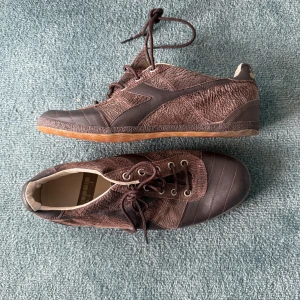 Bruna sneakers från Diadora i hajskinn - Helt unika sneakers från Diadora. Tillverkade av hajskinn. Den här modellen tillverkades aldrig kommersiellt. Nypris var 5.000kr för 15 år sedan. De är helt nya, har aldrig använt dem. Vill helst att köpt vara hämtas på Södermalm i Stockholm.