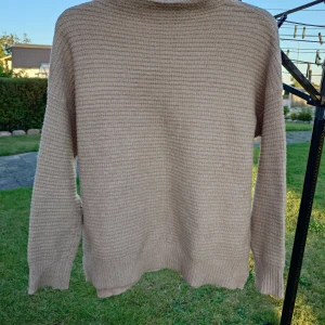 Beige stickad tröja från Amisu - Säljer en beige stickad tröja från Amisu i storlek XS. Tröjan har en enkel, rund hals och ett diskret rutmönster i stickningen. Långärmad och mjuk, perfekt för att hålla dig varm under kyliga dagar. Passar dig som gillar stilrena och neutrala färger.