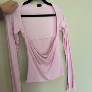 Ljusrosa långärmad topp - Säljer en ljusrosa långärmad topp. Toppen har en tight passform och är tillverkad i mjuk bomullsmix. Perfekt för dig som gillar trendiga och feminina plagg.