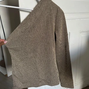 Beige ribbad stickad tröja - Säljer en beige ribbad stickad tröja med lång ärm och figurnära passform. Tröjan har en enkel och stilren design, perfekt att matcha med jeans eller kjol. Materialet är mjukt och stretchigt för extra komfort. Lånad bild!