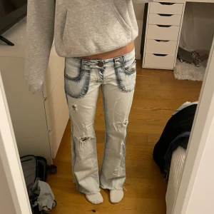 Ljusblå bootcut jeans med slitningar och kontrastsömmar - Säljer ett par ljusblå bootcut jeans med slitningar på benen och markerade kontrastsömmar. Jeansen har stora fickor fram och bak. Jättesnygga och passar mig som är 160-165 och har xs/s. Innerbenslängden är 75 och midjemåttet är 35 cm❤️