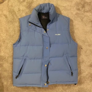 Dunväst - Supertrendig Peak performance dunväst från 00-talet. Retro och är sparsamt använd. Självklart äkta och säljer då den inte används mer. Perfekt nu till hösten 